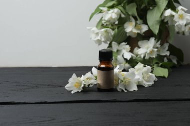Tıbbi ve kozmetik kullanım için indirme şişeleri ve ahşap masada yasemin çiçekleri. Doğal kozmetik ürünleri ve temel eko-ambalaj, spa konsepti.