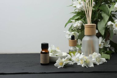 Tıbbi ve kozmetik kullanım için indirme şişeleri ve ahşap masada yasemin çiçekleri. Doğal kozmetik ürünleri ve temel eko-ambalaj, spa konsepti.
