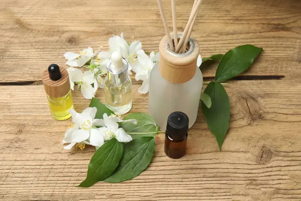 Tıbbi ve kozmetik kullanım için indirme şişeleri ve ahşap masada yasemin çiçekleri. Doğal kozmetik ürünleri ve temel eko-ambalaj, spa konsepti.