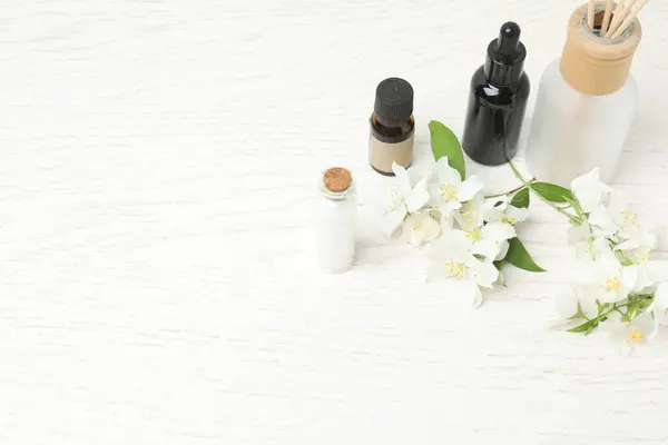 Tıbbi ve kozmetik kullanım için indirme şişeleri ve ahşap masada yasemin çiçekleri. Doğal kozmetik ürünleri ve temel eko-ambalaj, spa konsepti.