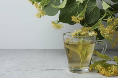 Ahşap zemin üzerinde ıhlamur çiçekleri olan bir fincan bitki çayı.