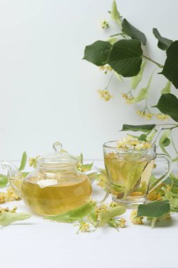 Ahşap zemin üzerinde ıhlamur çiçekleri olan bir fincan bitki çayı.