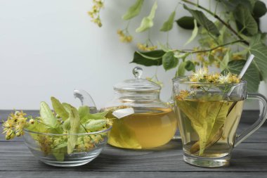 Ahşap zemin üzerinde ıhlamur çiçekleri olan bir fincan bitki çayı.