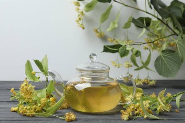 Ahşap zemin üzerinde ıhlamur çiçekleri olan bir fincan bitki çayı.