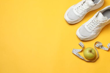 Sarı arka planda spor aletleri seti, üst manzara.