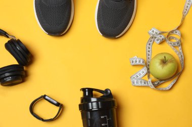 Sarı arka planda spor aletleri seti, üst manzara.