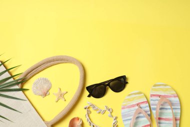 Yukarıdan gelen tropik titreşimler. Hasır şapka, güneş gözlüğü, ananas, hasır çanta, sarı arka planda plaj aksesuarları. Reklam ya da metin kaplamaları için mükemmel