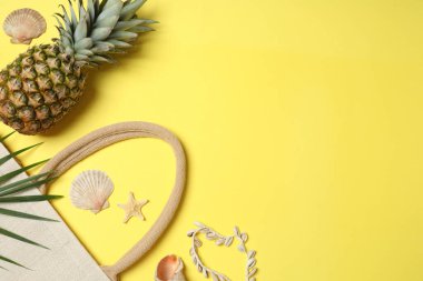 Yukarıdan gelen tropik titreşimler. Hasır şapka, güneş gözlüğü, ananas, hasır çanta, sarı arka planda plaj aksesuarları. Reklam ya da metin kaplamaları için mükemmel
