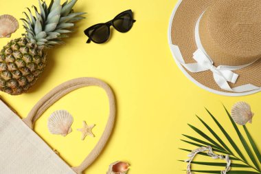 Yukarıdan gelen tropik titreşimler. Hasır şapka, güneş gözlüğü, ananas, hasır çanta, sarı arka planda plaj aksesuarları. Reklam ya da metin kaplamaları için mükemmel