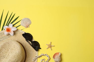 Yukarıdan gelen tropik titreşimler. Hasır şapka, güneş gözlüğü, ananas, hasır çanta, sarı arka planda plaj aksesuarları. Reklam ya da metin kaplamaları için mükemmel