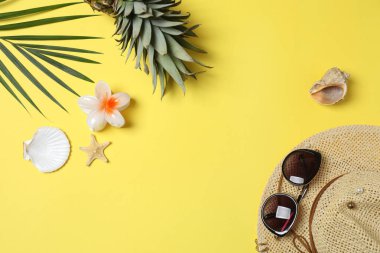 Yukarıdan gelen tropik titreşimler. Hasır şapka, güneş gözlüğü, ananas, hasır çanta, sarı arka planda plaj aksesuarları. Reklam ya da metin kaplamaları için mükemmel