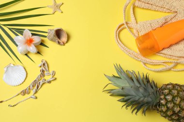 Yukarıdan gelen tropik titreşimler. Hasır şapka, güneş gözlüğü, ananas, hasır çanta, sarı arka planda plaj aksesuarları. Reklam ya da metin kaplamaları için mükemmel