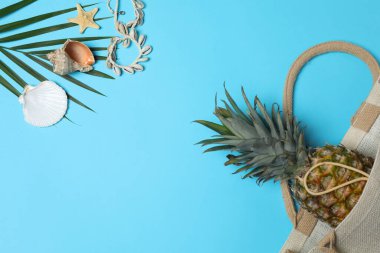 Yukarıdan gelen tropik titreşimler. Hasır şapka, güneş gözlüğü, ananas, hasır çanta, mavi arka planda plaj aksesuarları. Reklam ya da metin kaplamaları için mükemmel