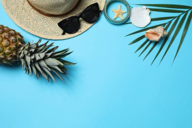 Yukarıdan gelen tropik titreşimler. Hasır şapka, güneş gözlüğü, ananas, hasır çanta, mavi arka planda plaj aksesuarları. Reklam ya da metin kaplamaları için mükemmel