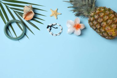 Yukarıdan gelen tropik titreşimler. Hasır şapka, güneş gözlüğü, ananas, hasır çanta, mavi arka planda plaj aksesuarları. Reklam ya da metin kaplamaları için mükemmel