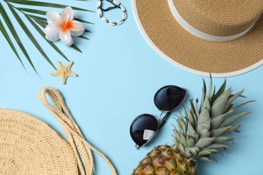 Yukarıdan gelen tropik titreşimler. Hasır şapka, güneş gözlüğü, ananas, hasır çanta, mavi arka planda plaj aksesuarları. Reklam ya da metin kaplamaları için mükemmel