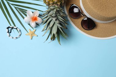 Yukarıdan gelen tropik titreşimler. Hasır şapka, güneş gözlüğü, ananas, hasır çanta, mavi arka planda plaj aksesuarları. Reklam ya da metin kaplamaları için mükemmel