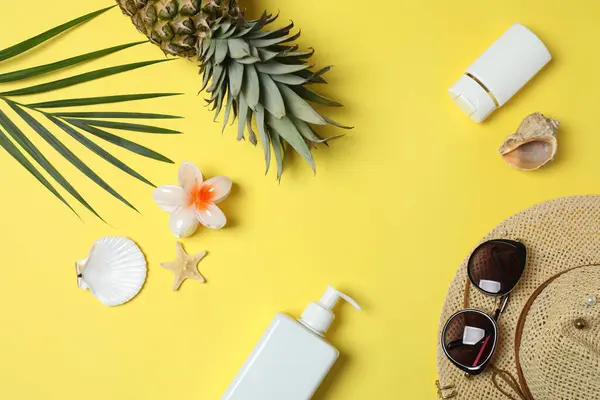 Yukarıdan gelen tropik titreşimler. Hasır şapka, güneş gözlüğü, ananas, hasır çanta, sarı arka planda plaj aksesuarları. Reklam ya da metin kaplamaları için mükemmel