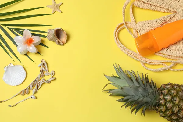 Yukarıdan gelen tropik titreşimler. Hasır şapka, güneş gözlüğü, ananas, hasır çanta, sarı arka planda plaj aksesuarları. Reklam ya da metin kaplamaları için mükemmel
