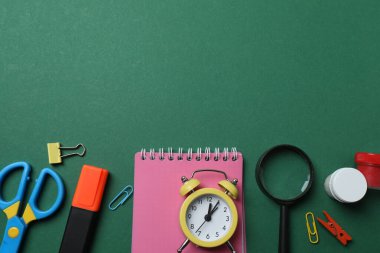 Okul malzemelerinin, kalemlerin, silgilerin, ataçların ve defterlerin yeşil arka planda üst görüntüsü. Eğitimle ilgili konular için ideal resim,