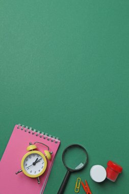 Okul malzemelerinin, kalemlerin, silgilerin, ataçların ve defterlerin yeşil arka planda üst görüntüsü. Eğitimle ilgili konular için ideal resim,