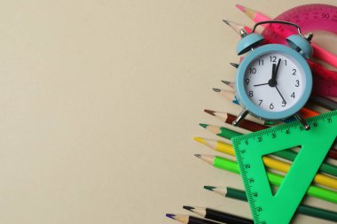 Okul malzemelerinin, kalemlerin, silgilerin, ataçların ve not defterlerinin bej bir arkaplandaki en üst görüntüsü. Eğitimle ilgili konular için ideal resim,