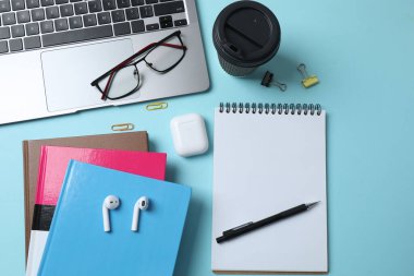 dizüstü bilgisayar gözlükleri kahve kulaklıkları mavi arkaplan üzerinde not defteri ve metin için yer var.