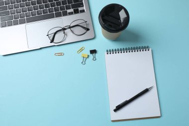 dizüstü bilgisayar gözlükleri kahve kulaklıkları mavi arkaplan üzerinde not defteri ve metin için yer var.