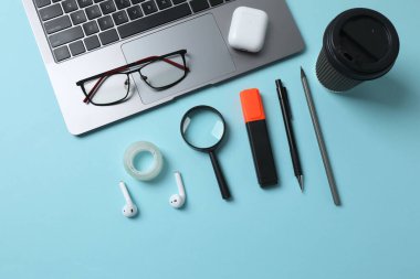 dizüstü bilgisayar gözlükleri kahve kulaklıkları mavi arkaplan üzerinde not defteri ve metin için yer var.