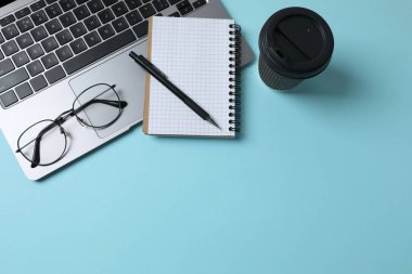 dizüstü bilgisayar gözlükleri kahve kulaklıkları mavi arkaplan üzerinde not defteri ve metin için yer var.