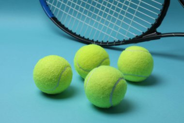 Tenis raketi, spor şişesi ve top mavi arka planda.