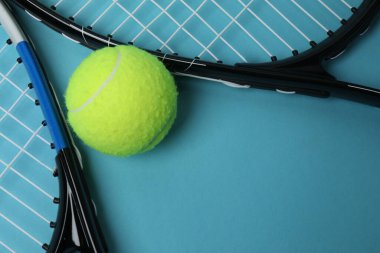 Tenis raketi, spor şişesi ve top mavi arka planda.