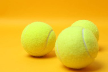 Tenis raketi, spor şişesi ve top sarı arka planda.