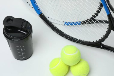 Tenis raketi, spor şişesi ve beyaz arka planda top.