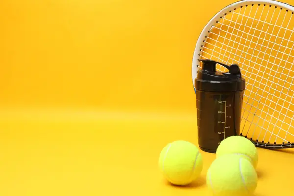 Tenis raketi, spor şişesi ve top sarı arka planda.