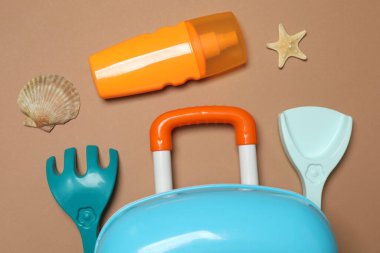 Çocuğun seyahat çantası, oyuncaklar, bej arka planda şekerli krema.