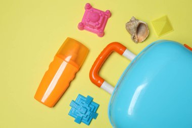 Çocuğun seyahat çantası, oyuncaklar, sarı arka planda tatlı krema.