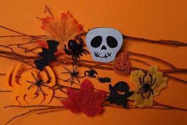 Kafatası, keneler, turuncu akçaağaç yaprakları, yarasalar, turuncu arkaplandaki örümcekler ile Cadılar Bayramı.