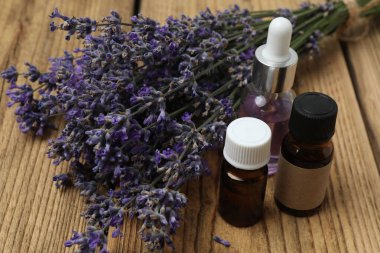 Lavanta yağlı şişeler, ahşap arka planda lavanta.