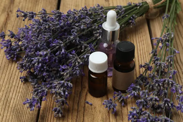 Lavanta yağlı şişeler, ahşap arka planda lavanta.