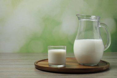 Tahta zemin üzerinde süt olan cam ve sürahi.