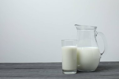 Gri ahşap arka planda, sütlü bardak ve sürahi.