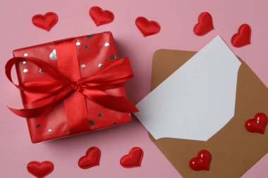 Pembe arkaplanda metin için yeri olan hediye kutusu ve zarf