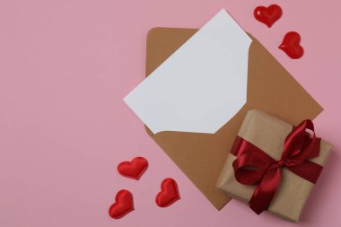 Pembe arkaplanda metin için yeri olan hediye kutusu ve zarf