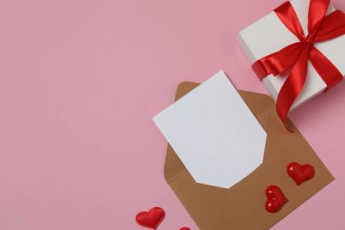 Pembe arkaplanda metin için yeri olan hediye kutusu ve zarf