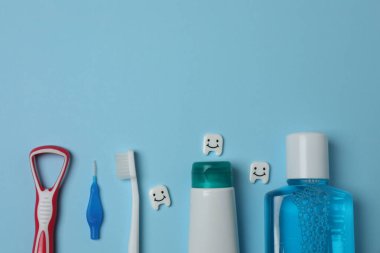 Diş fırçası, diş macunu, diş ipi, mavi arka planda diş fırçası.