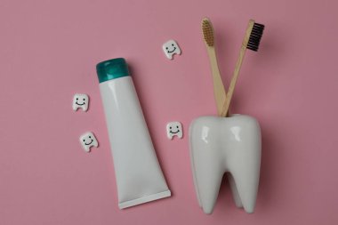 Diş fırçası, diş macunu, diş ipi, pembe arka planda diş fırçası.