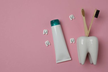 Diş fırçası, diş macunu, diş ipi, pembe arka planda diş fırçası.