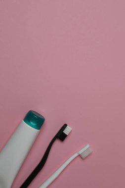 Diş fırçası, diş macunu, diş ipi, pembe arka planda diş fırçası.