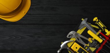 Siyah arkaplanda inşaat araçları ve kask.